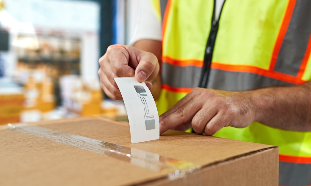 warehouse with boxes stored on black metal shelving units, forklift truck moving in front